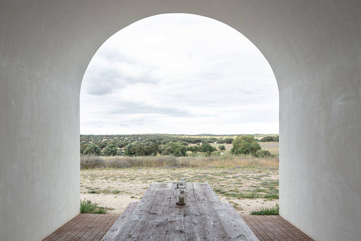 Une arche blanchie encadrant la plaine et une longue table, Alentejo
