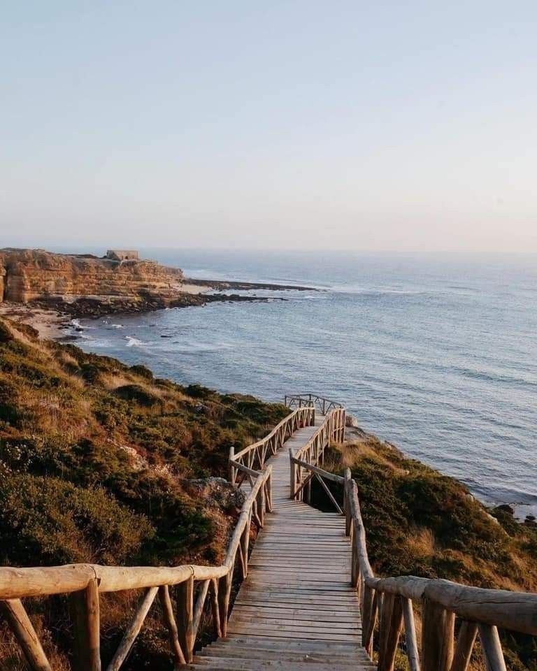 Une passerelle en bois vers la côte atlantique sauvage au crépuscule, Algarve