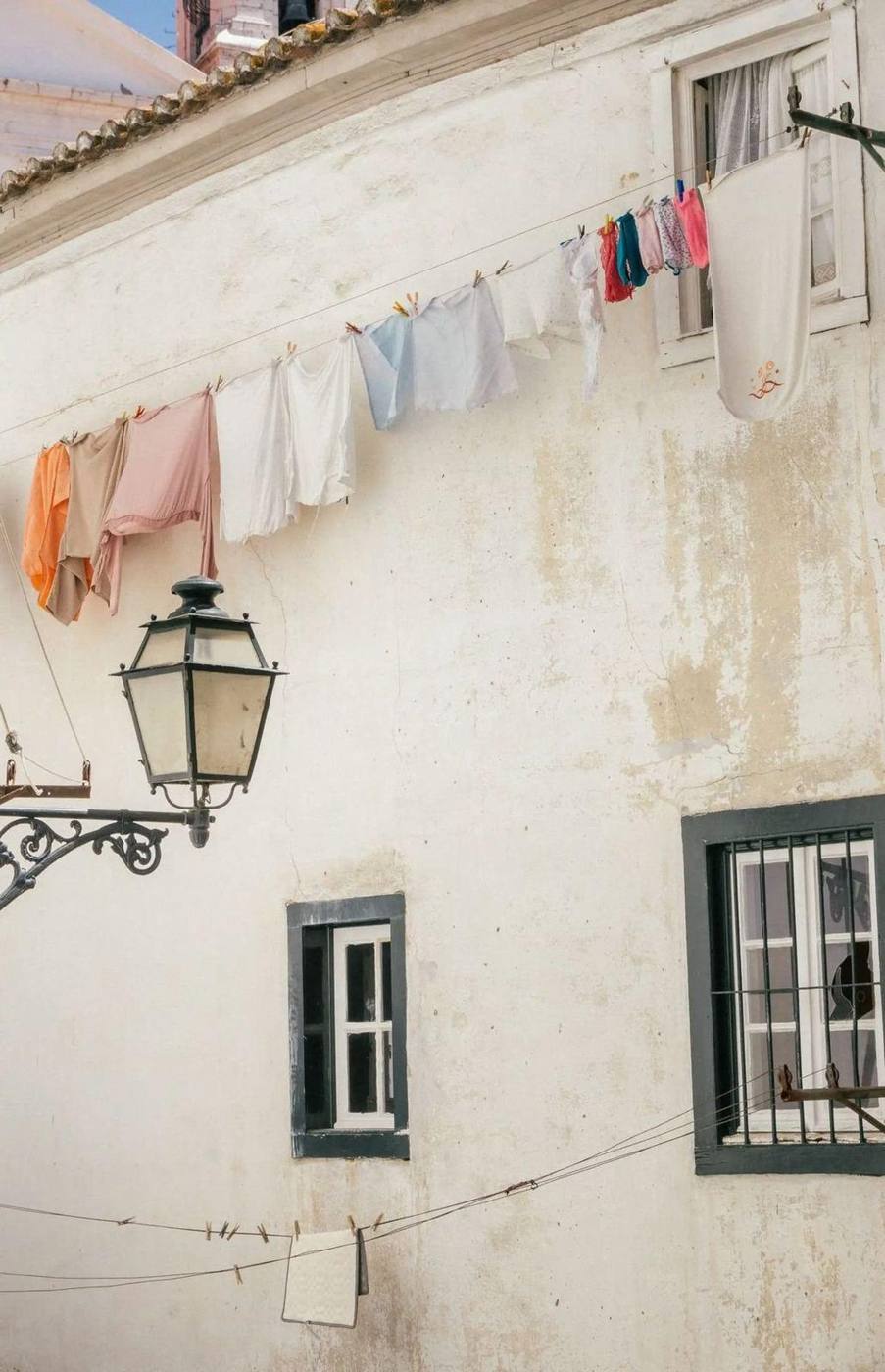 Linge coloré tendu au-dessus d'un lampadaire dans le vieux quartier, Lisbonne